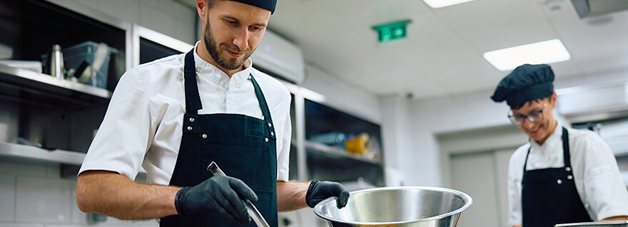 a chef and an apprentice working in a commercial kitchen.